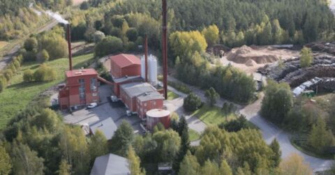 Ilmakuva Paimion Lämpökeskuksen lämpölaitoksesta, jonka ympärillä on metsää, puupolttoainevarastoja ja huoltoteitä. Laitoksen savupiipuista nousee höyryä.